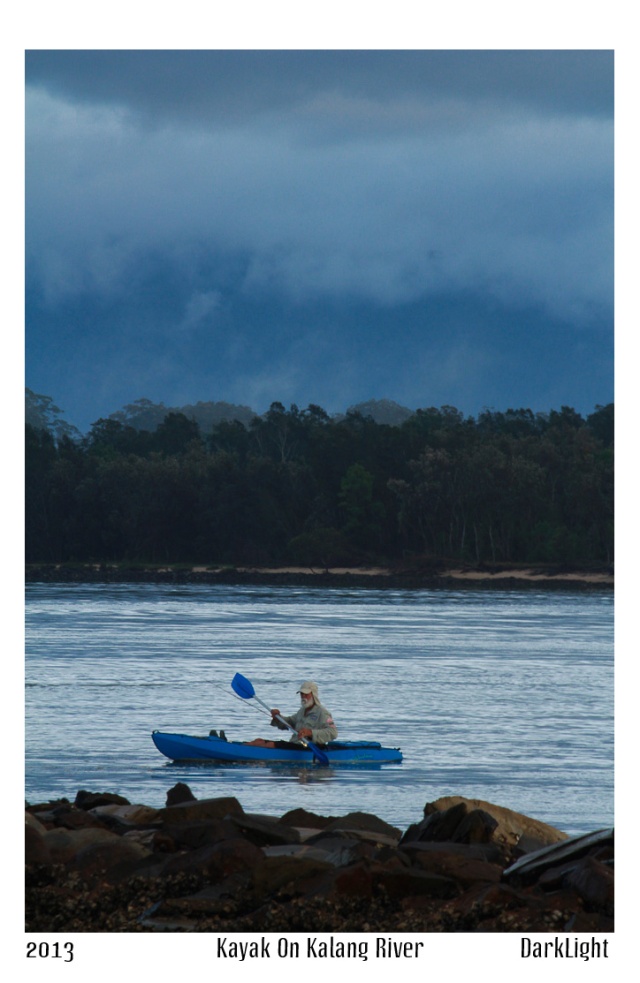 man paddiling blue kayak on river